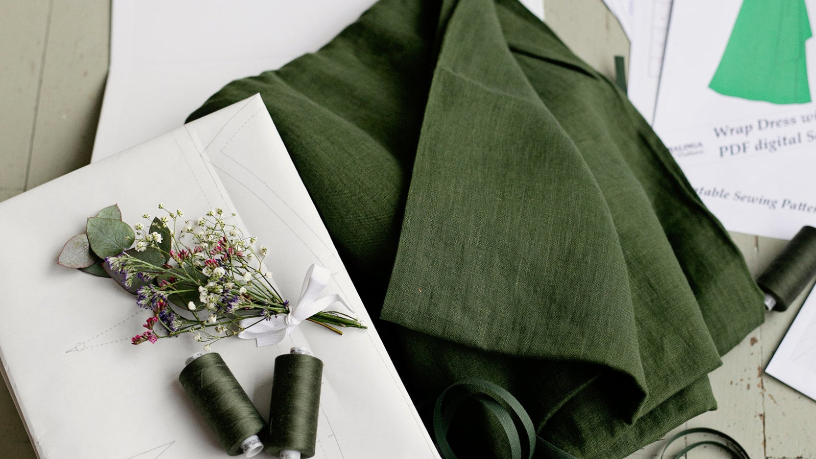 Green fabric, thread, sewing accessories and sewing patterns