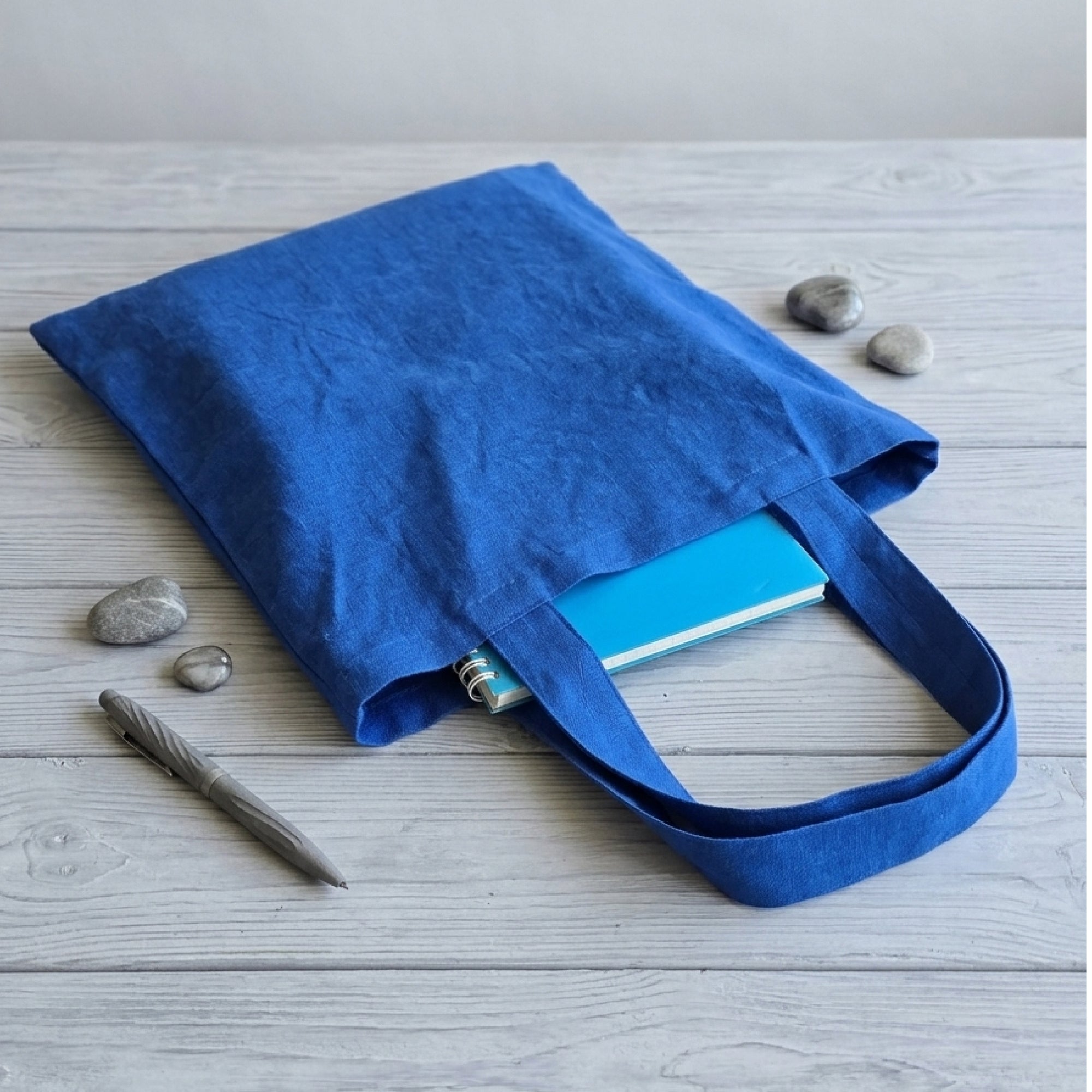 Blue tote bag with a notebook on a light wooden surface